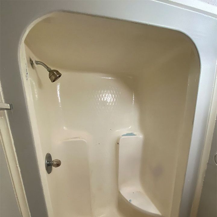 A white shower stall with a shower head and a seat.