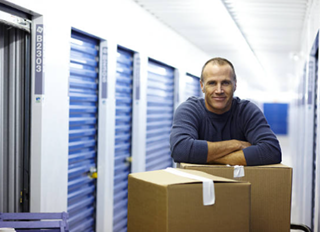 A man stands among boxes in a storage unit, highlighting the importance of self-storage units.