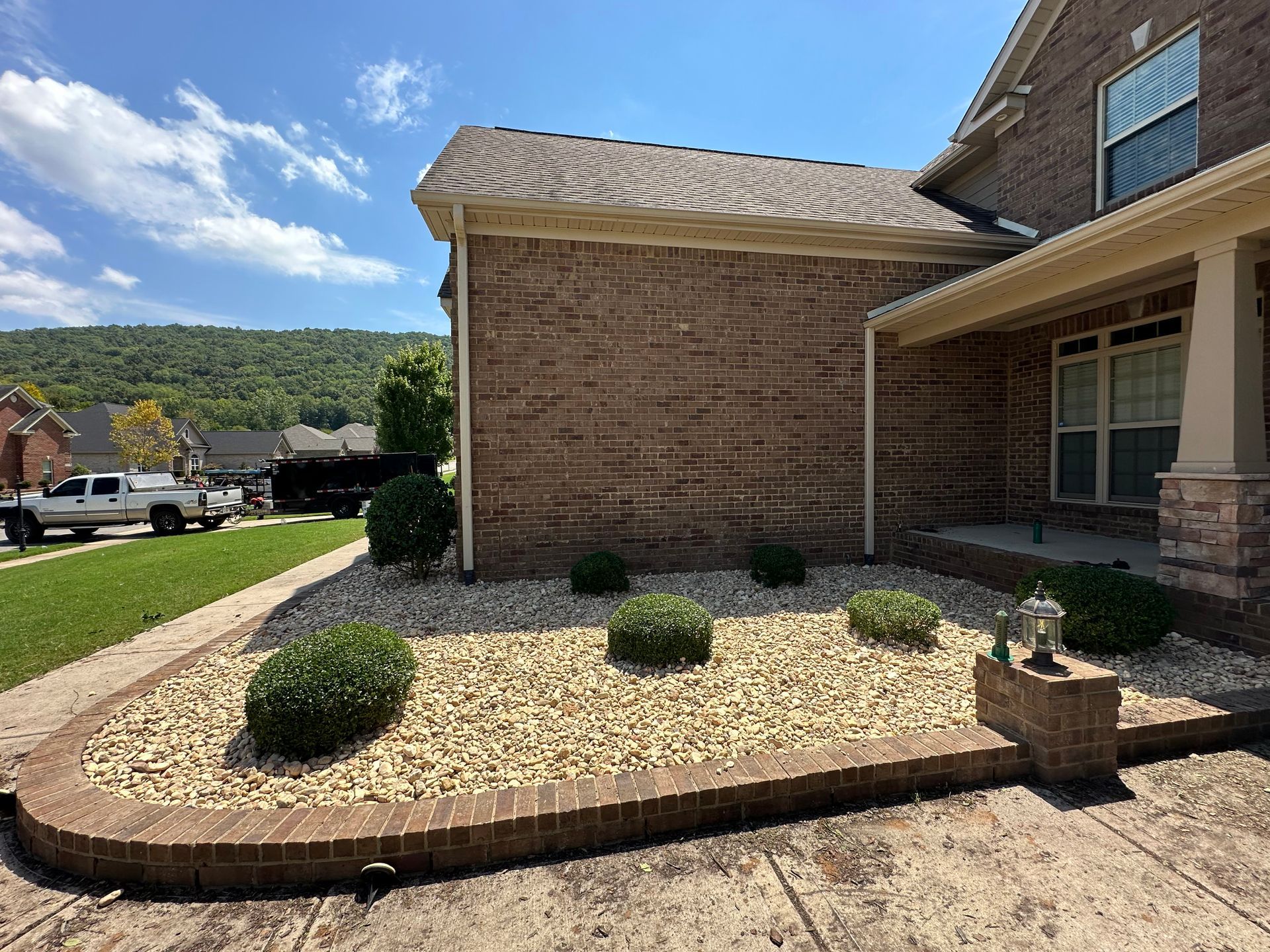 Brick home exterior with landscaped bed, bushes, and rocks.