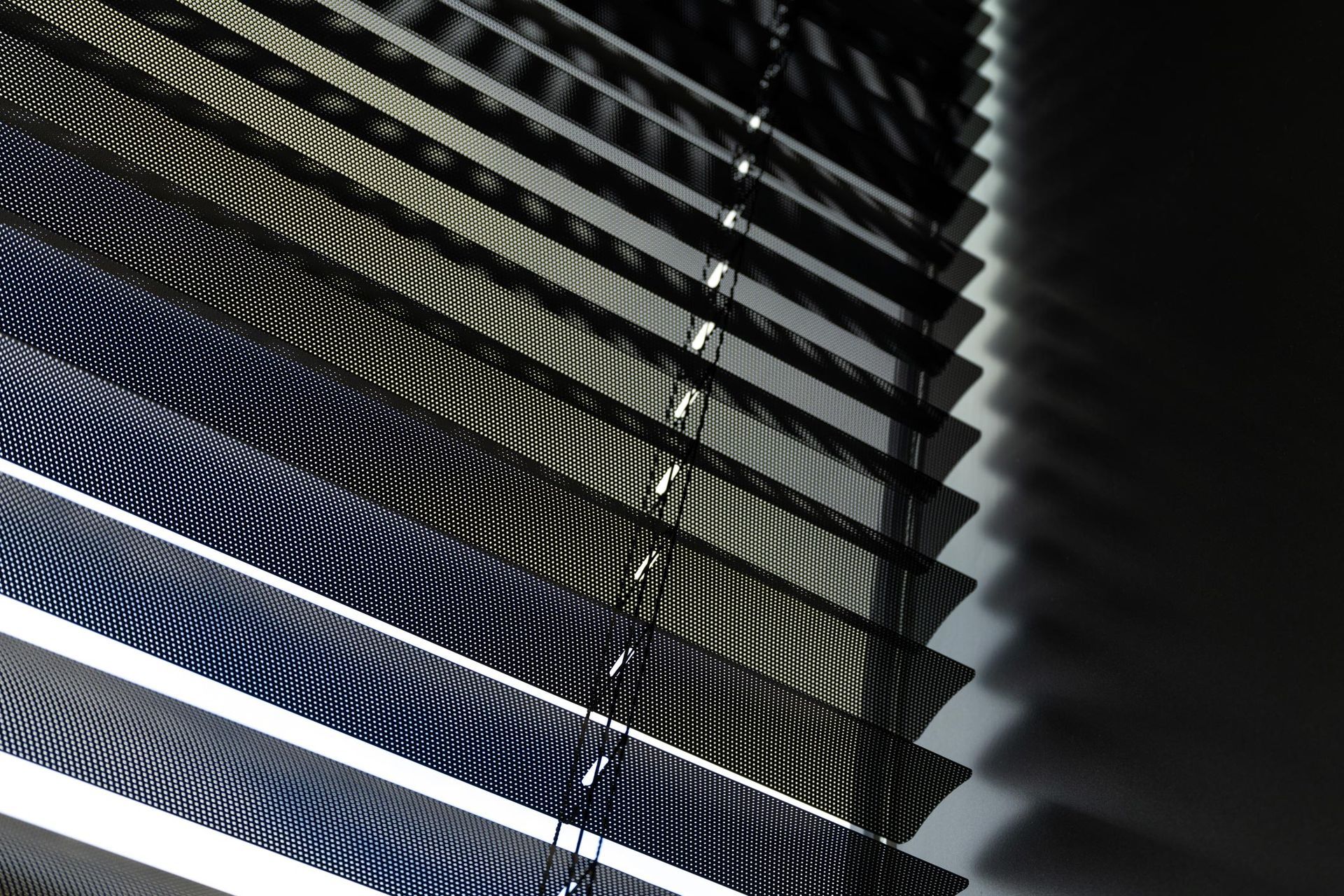 A close up of a row of blinds on a window.