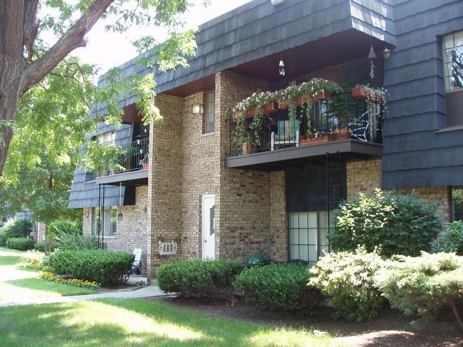 A brick apartment building with a balcony and flowers on it