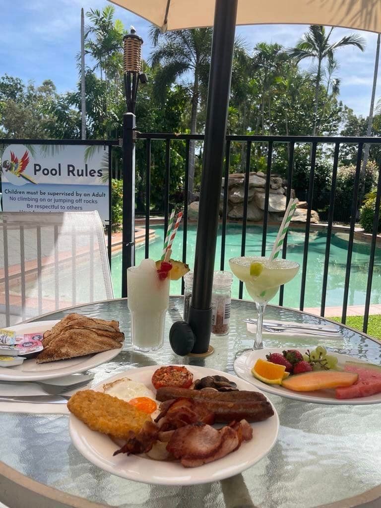 A Table With Plates Of Food And Drinks In Front Of A Pool — Heritage Resort in Nanum, QLD