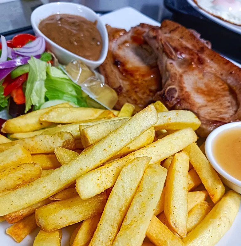 Plate of Food With French Fries, Meat, Vegetables and Sauces on a Table — Heritage Resort in Nanum, QLD