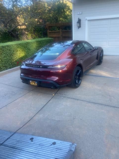 Burgundy Porsche sedan parked in a driveway, in front of a garage.