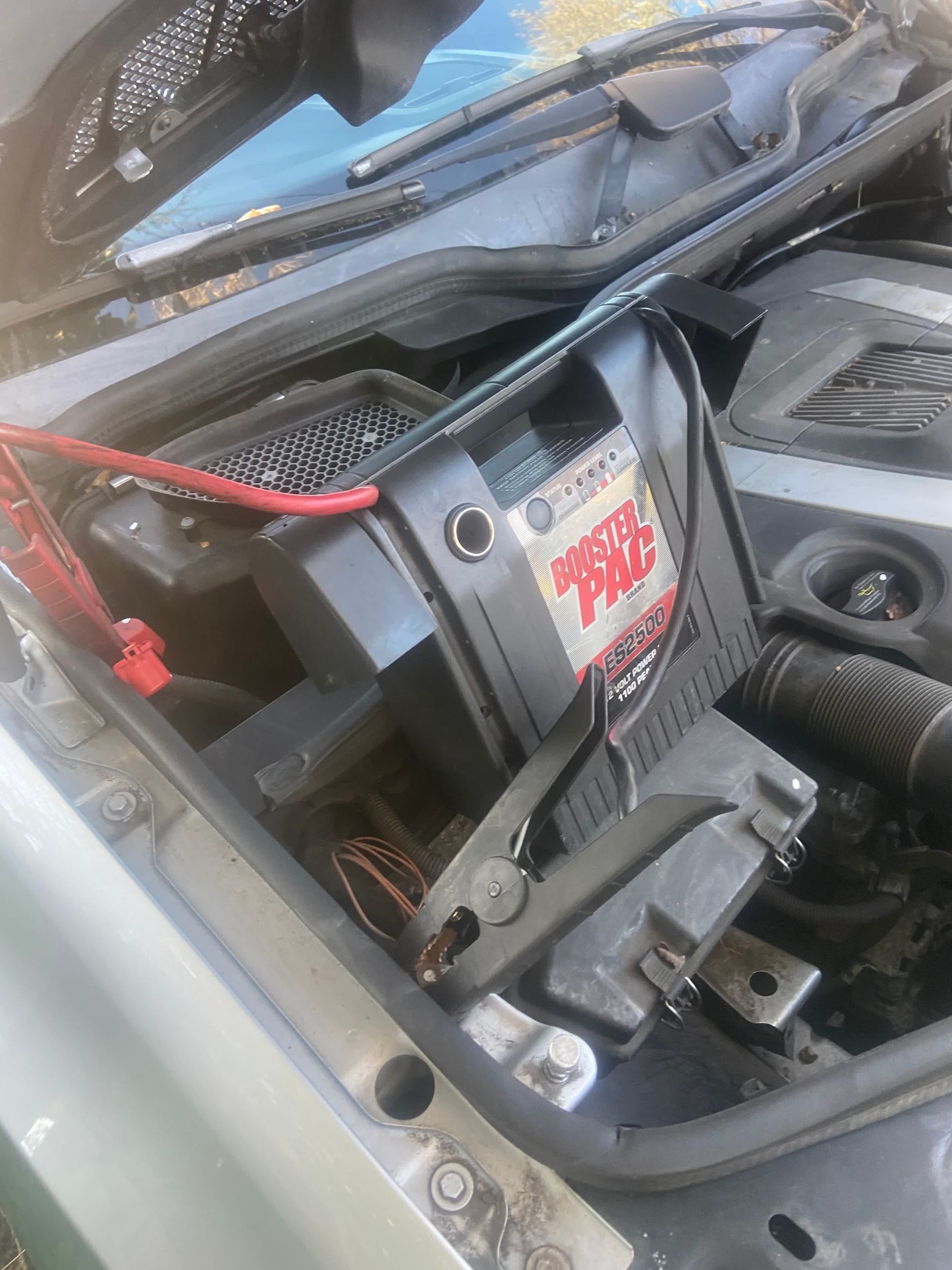 Car engine bay with a jumper pack connected to the battery.