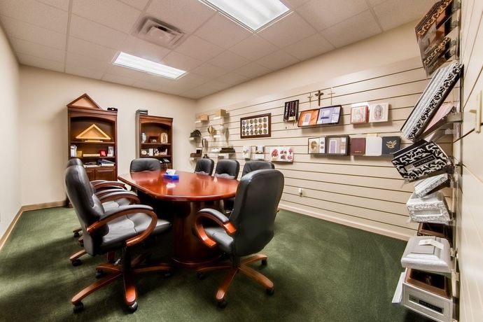 Small conference room with round wooden table, black chairs, shelves, and wall-mounted product displays
