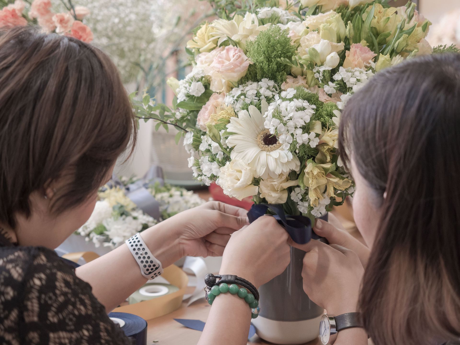 Two people arranging a pastel flower bouquet in a vase