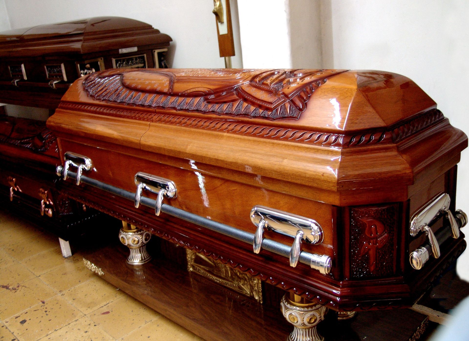 Polished mahogany coffin with silver handles in a funeral home room