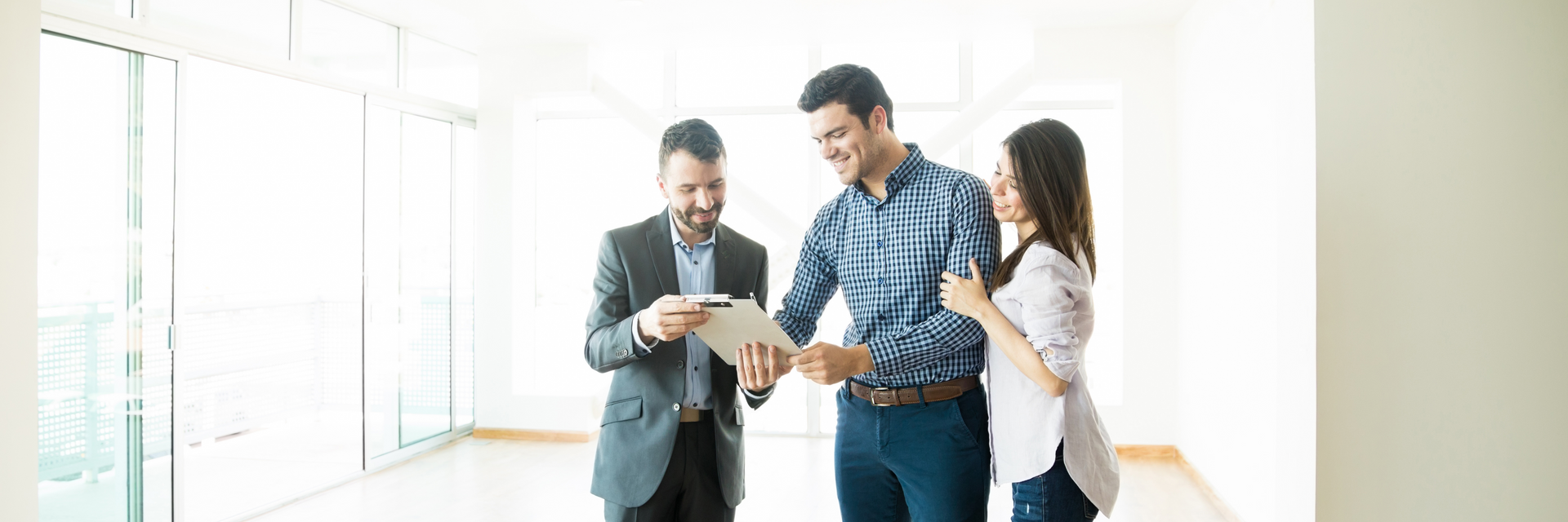 A man and a woman are looking at a tablet in an empty room.
