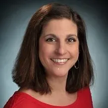 A woman in a red shirt is smiling for the camera.