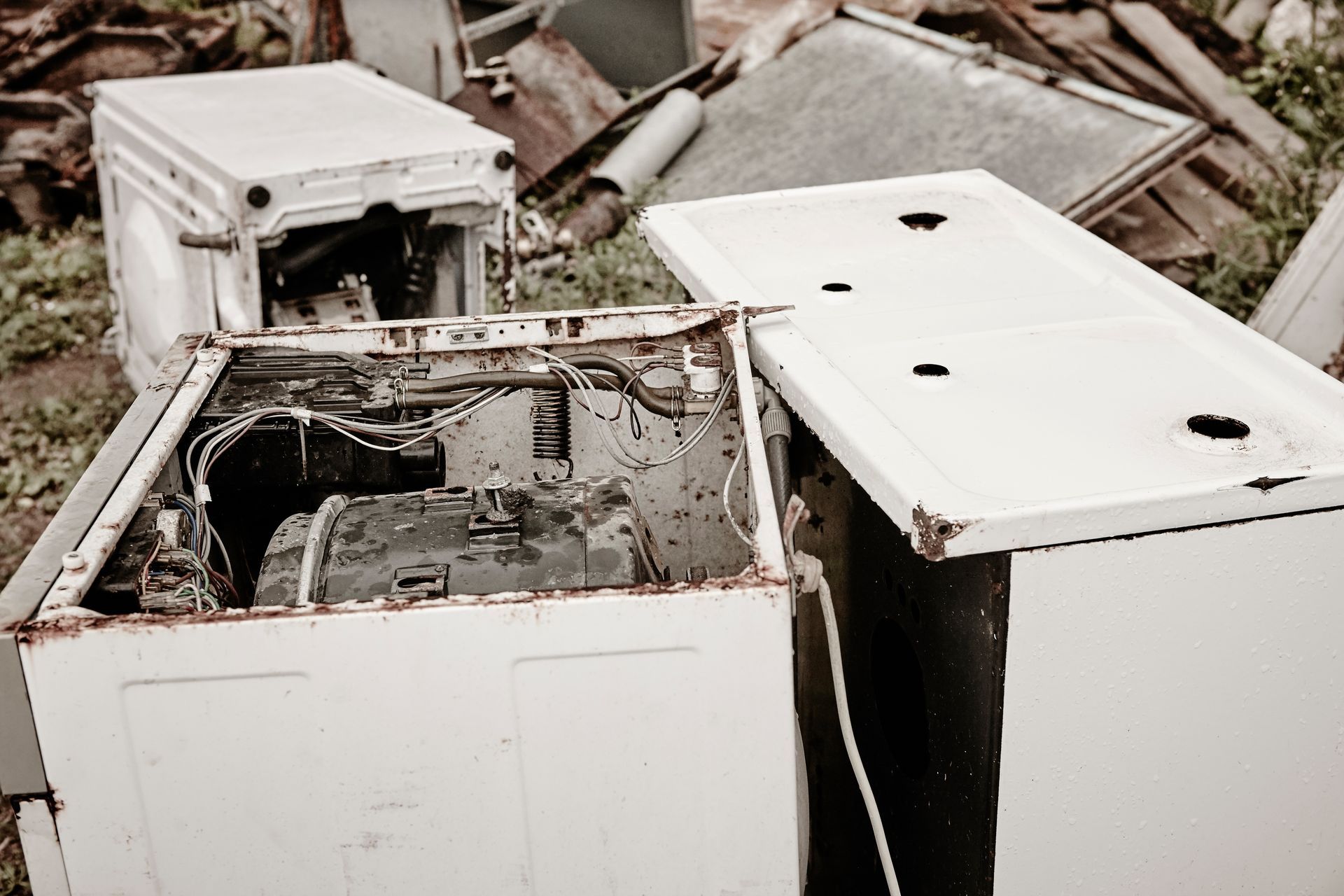 a broken refrigerator is sitting on top of a pile of junk .