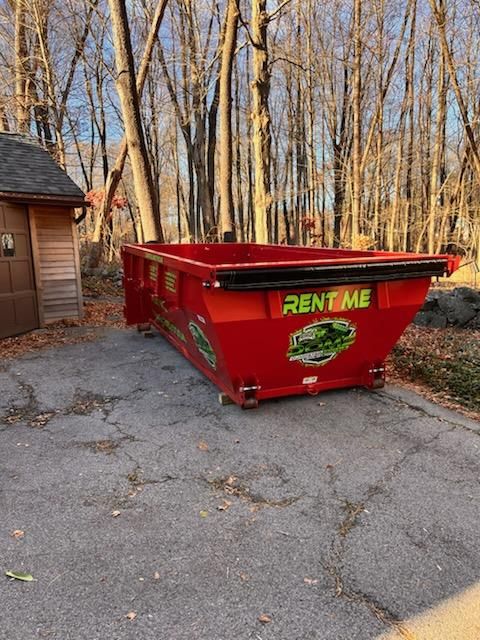 a red dumpster and a blue dumpster are sitting next to each other in a parking lot .