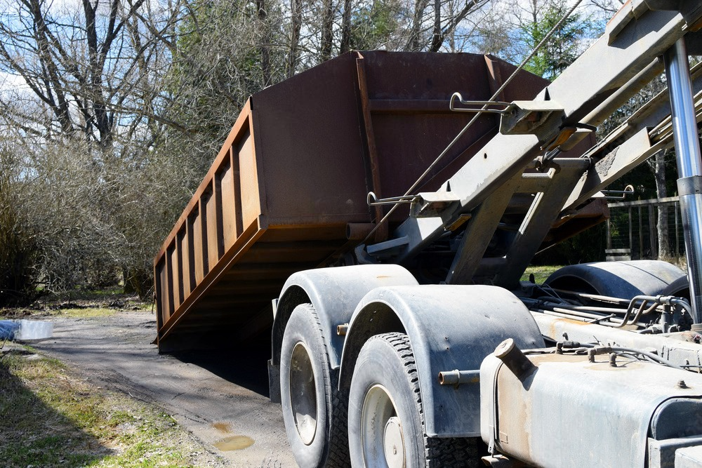 a dump truck is carrying a large brown dumpster on the back of it .