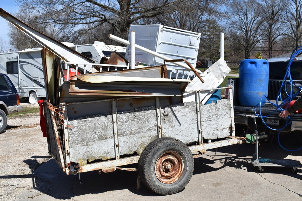 a trailer filled with junk is parked next to a truck .