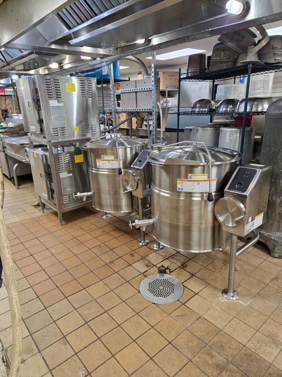 Chefs preparing plates in a busy restaurant kitchen, steam rising from stovetop.