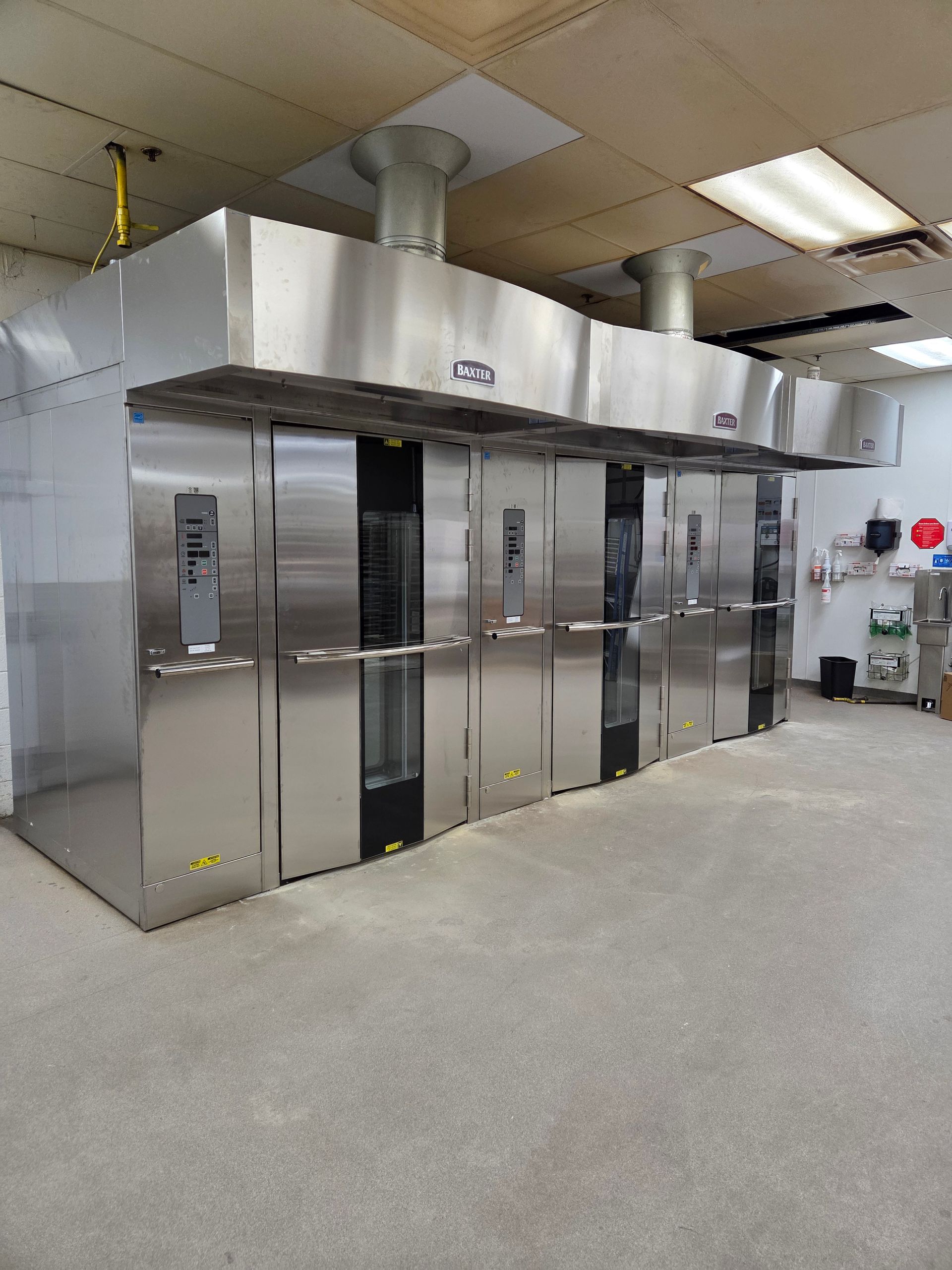Commercial stainless steel oven bank in a kitchen setting.