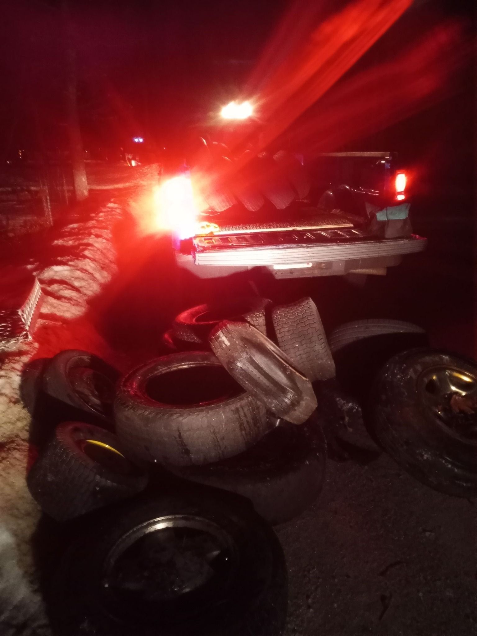 Pile of tires in front of a truck, illuminated by red light at night.