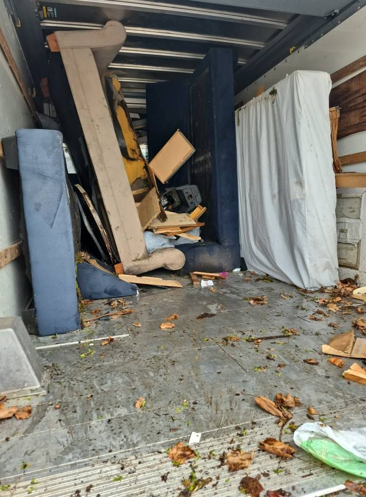 Inside a cluttered truck, filled with furniture, debris, and a mattress.