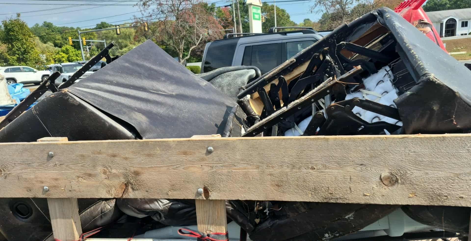 Pile of discarded furniture in a wooden truck bed on a sunny day.