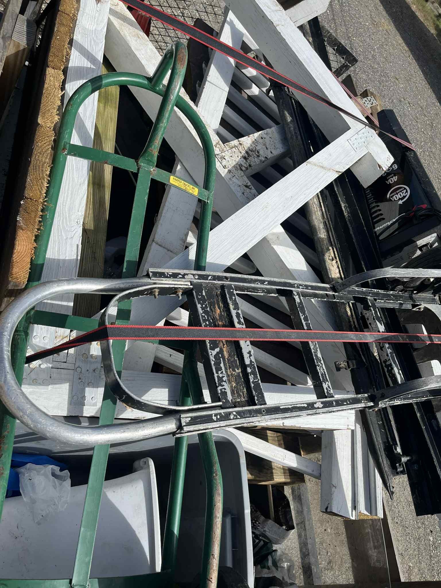 Green hand truck with black and white items, secured with red straps.