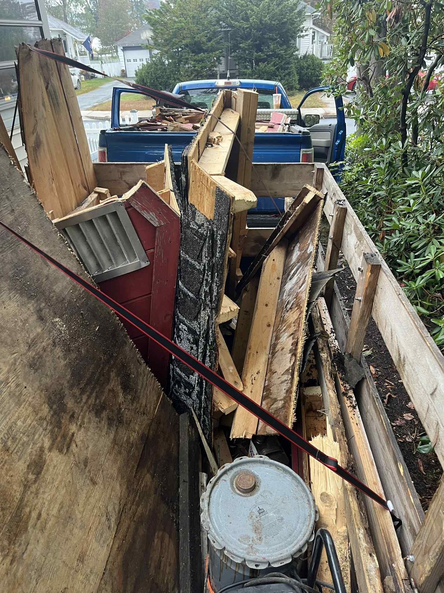 Debris-filled truck bed with wood, metal, and other construction materials.