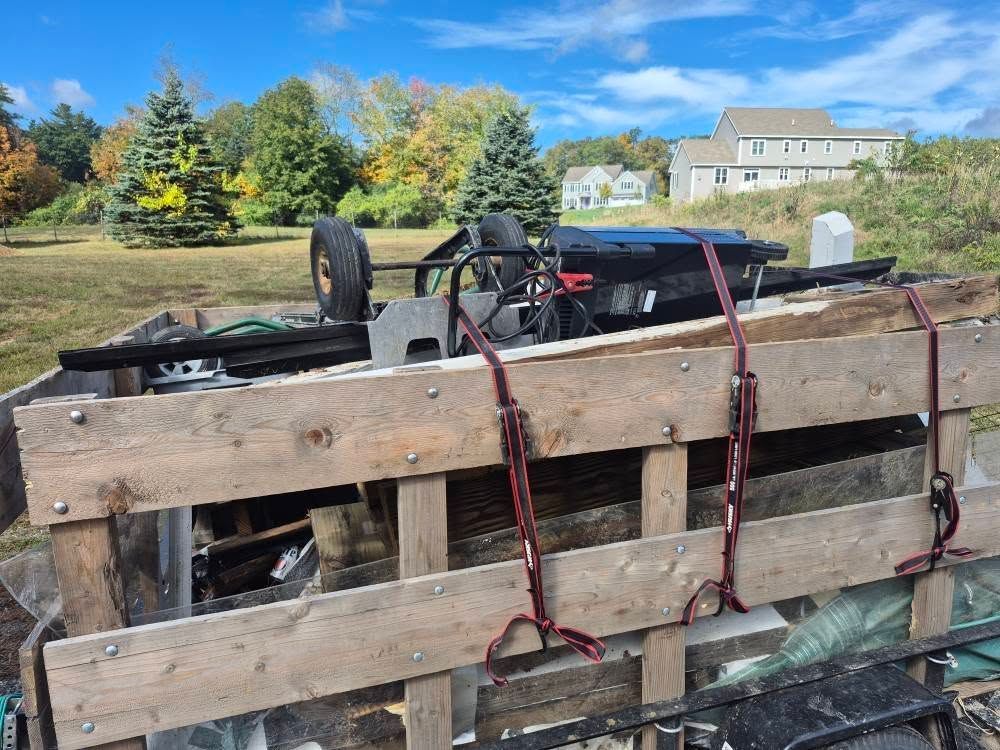 Pallet loaded with debris, strapped down. Outdoors, sunny day.