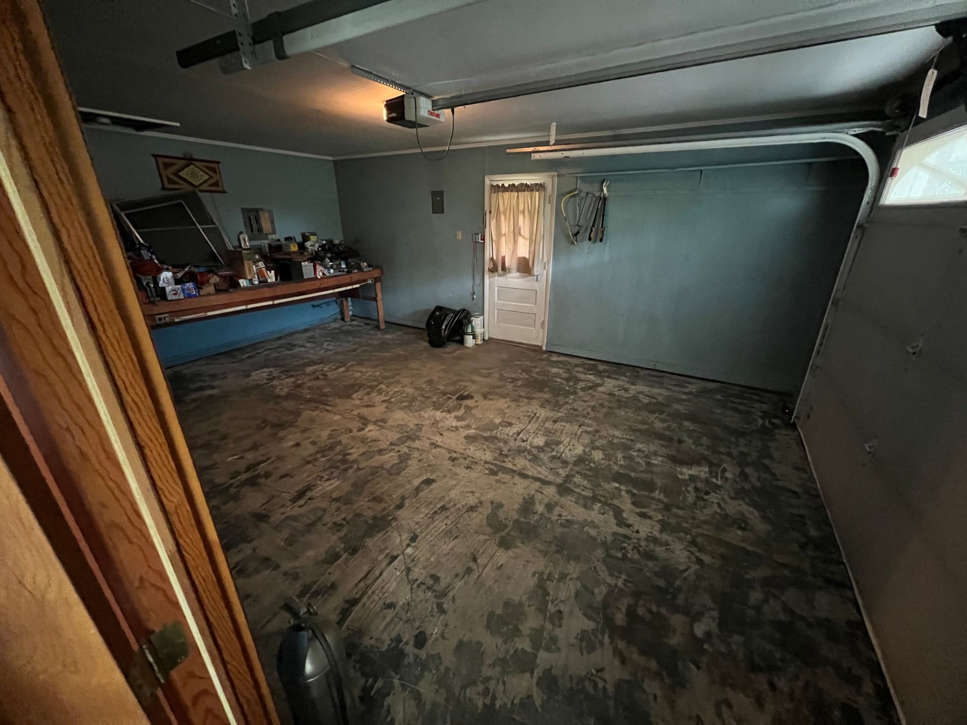 A garage with a garage door open and a carpeted floor.
