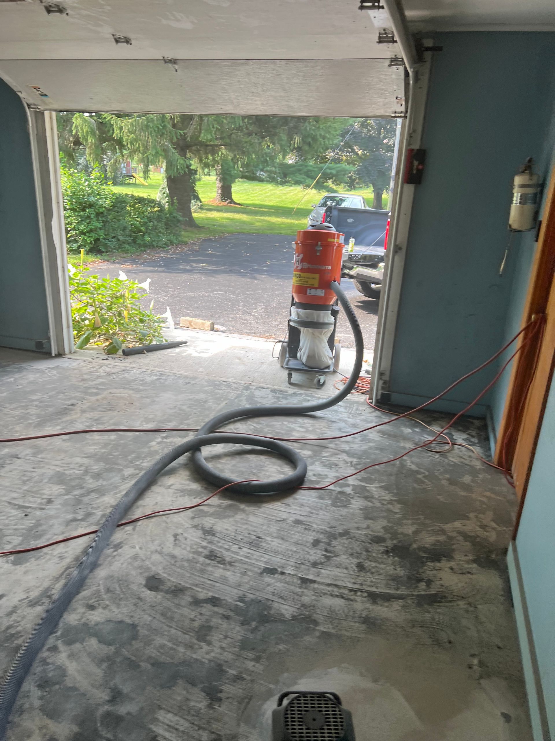 A vacuum cleaner is sitting in a garage next to a garage door.