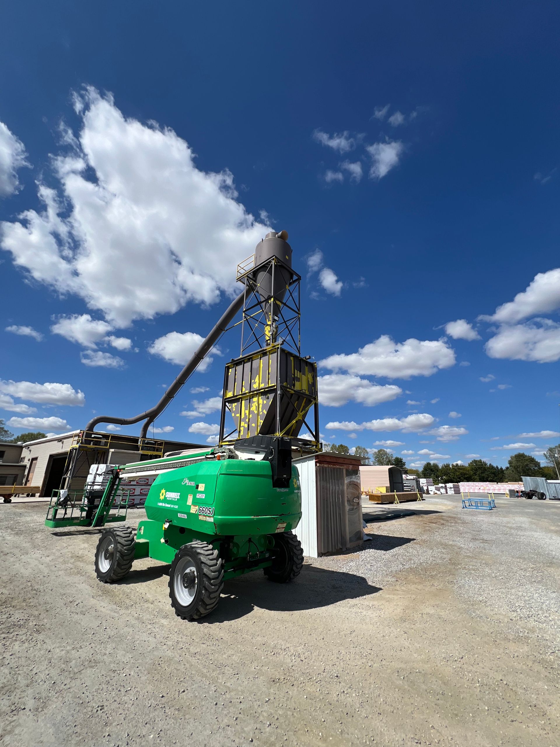 A green tractor is parked in a gravel lot.
