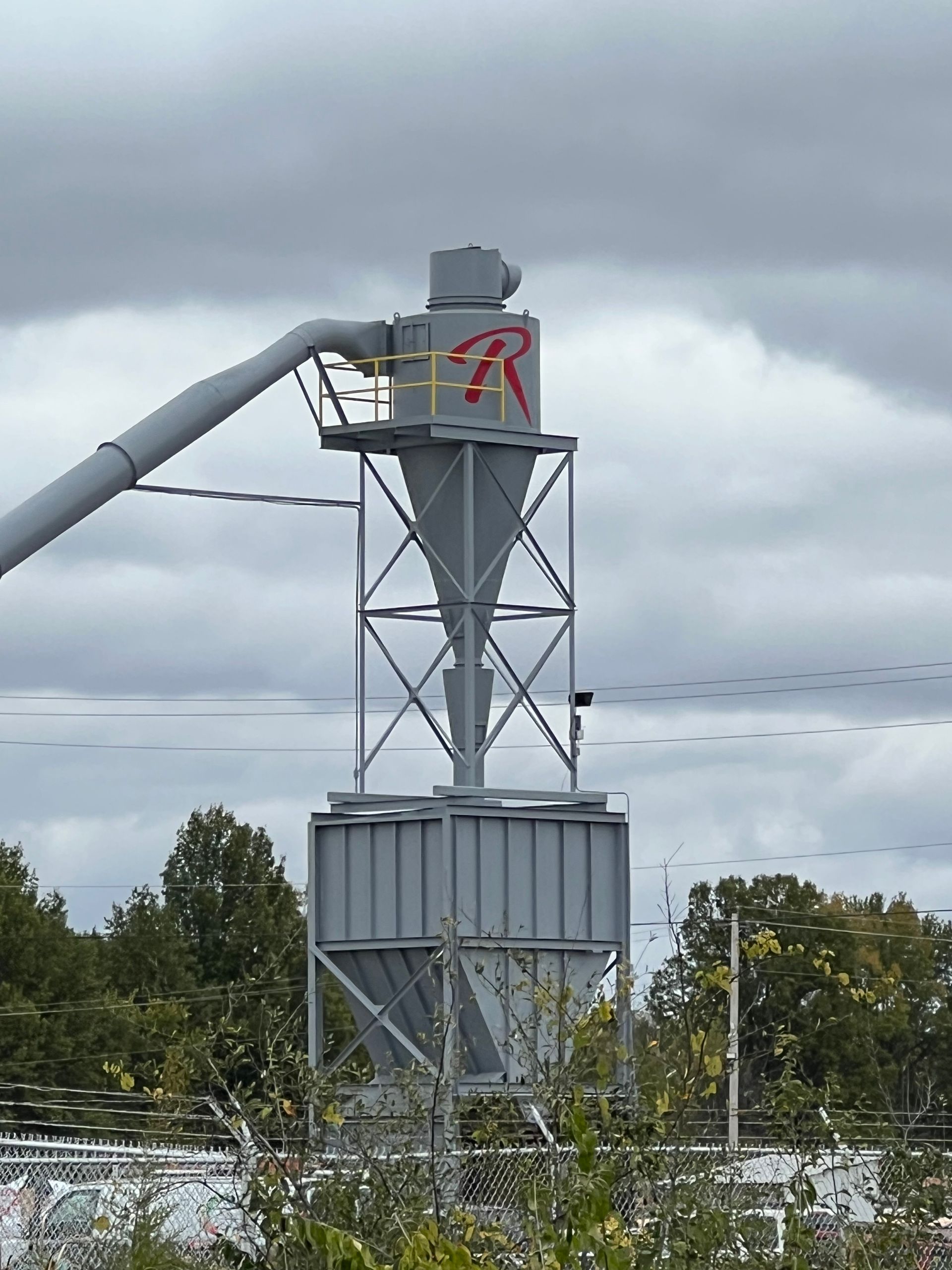 A crane is lifting a green vehicle in front of a building.