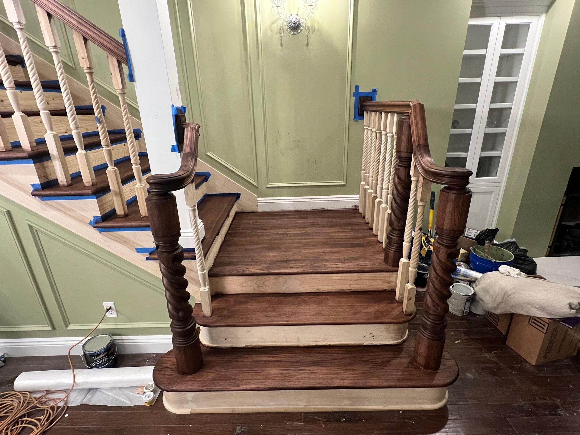 A wooden staircase is being painted in a living room.