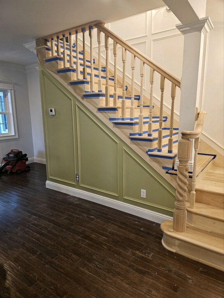 A wooden staircase is being painted in a living room.