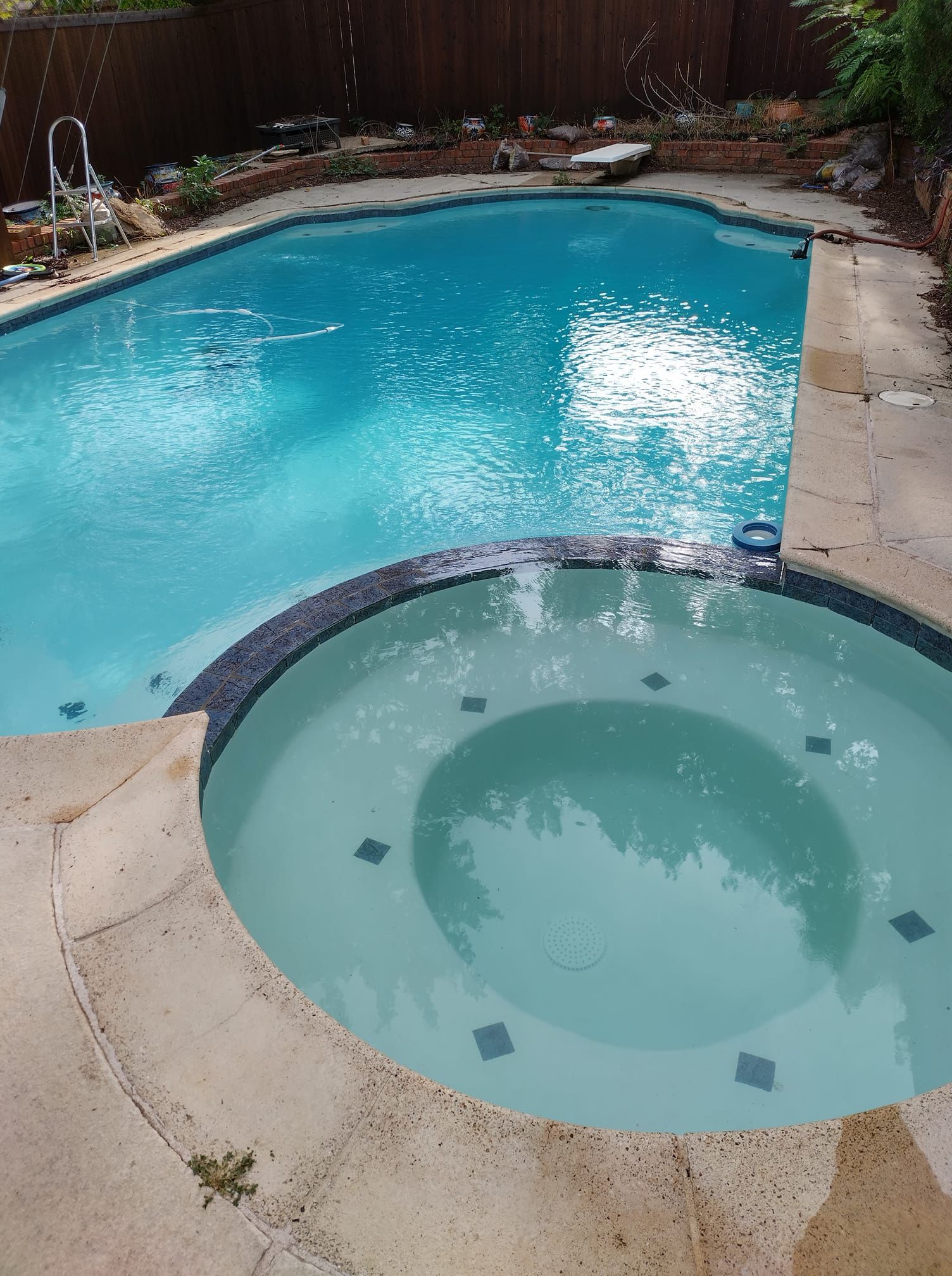 Swimming pool and hot tub with blue water, surrounded by concrete.