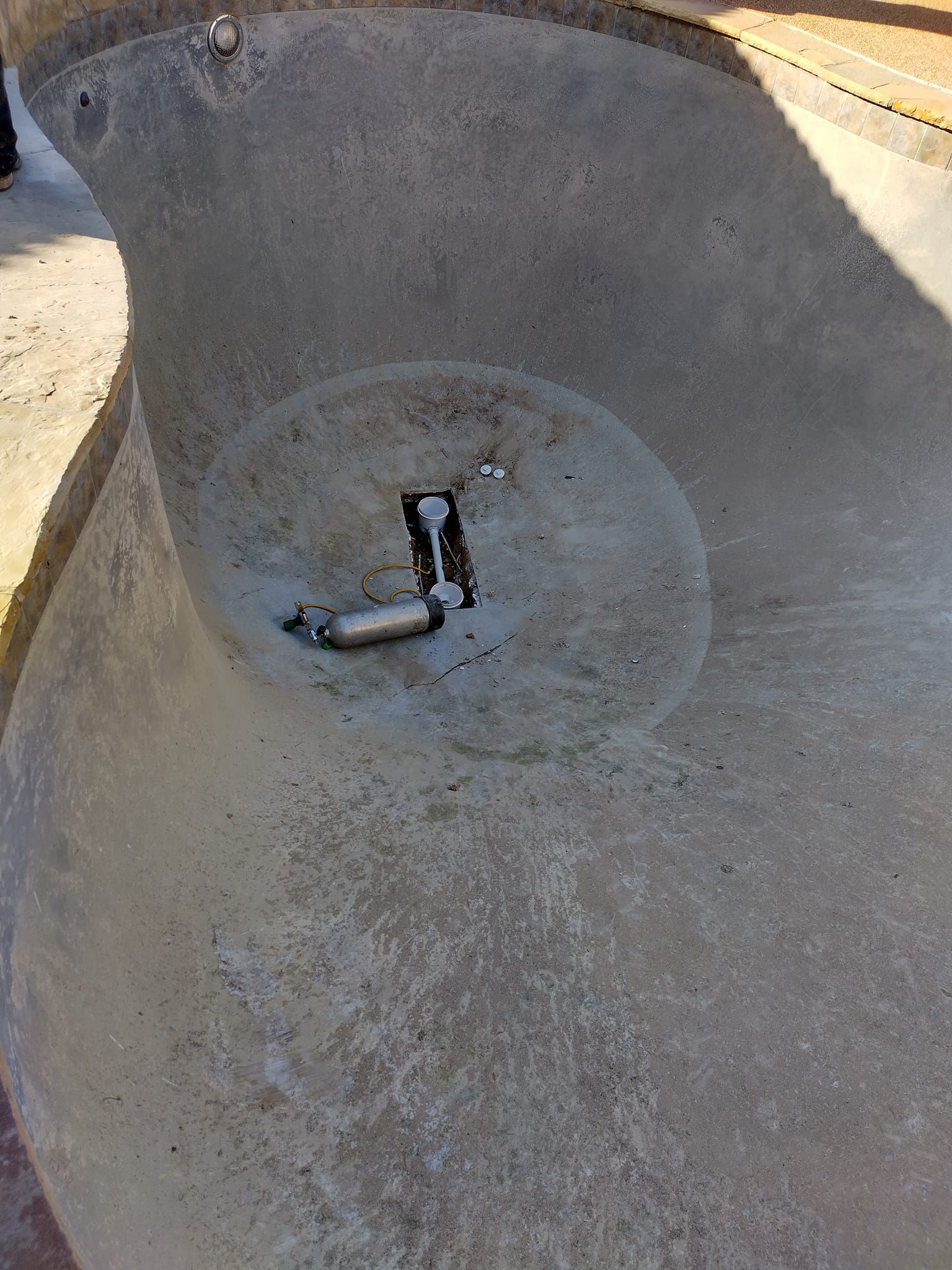 Concrete pool basin with central drain and light fixtures.