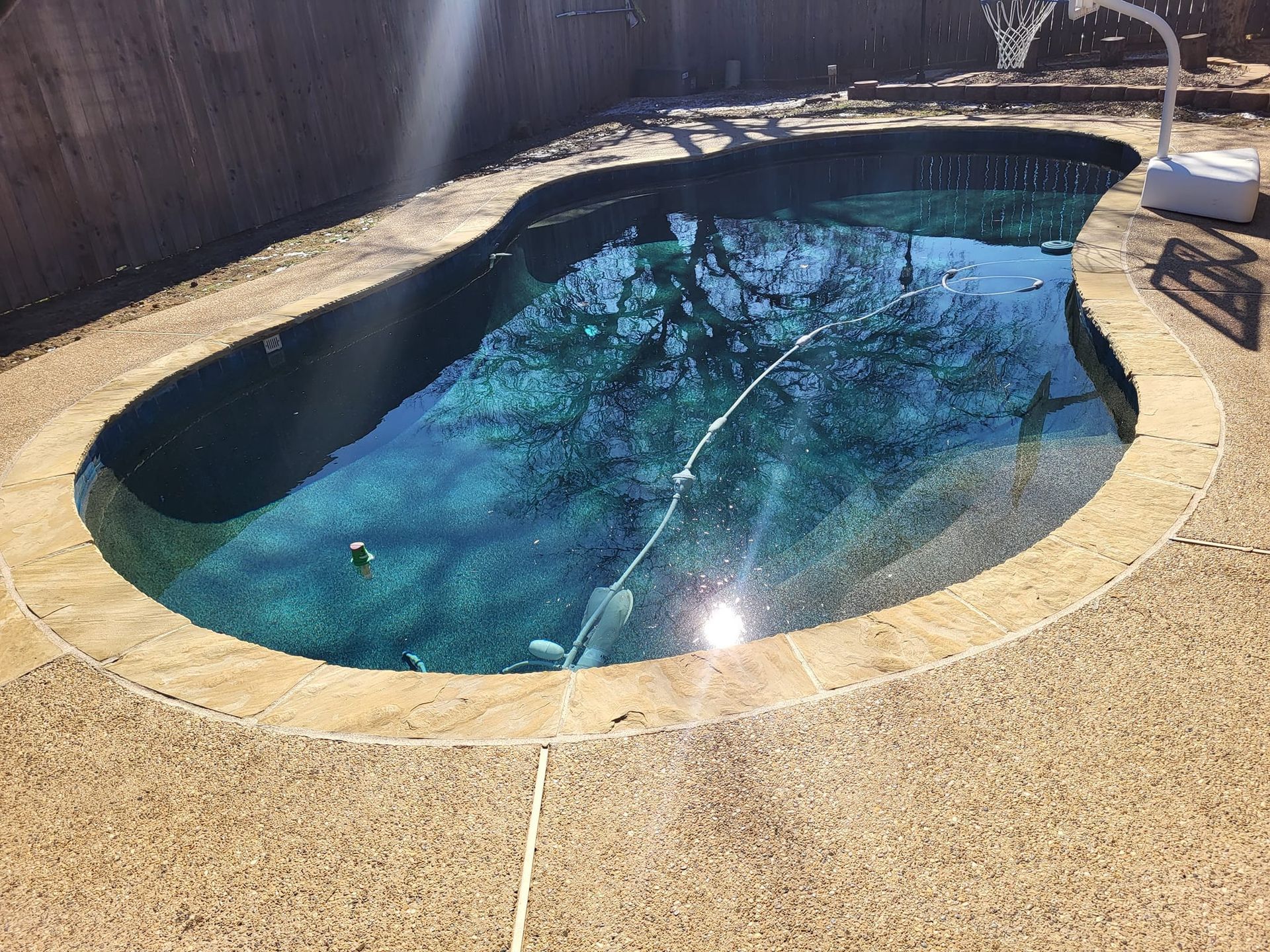 Pool with dark blue water and a tan concrete deck.