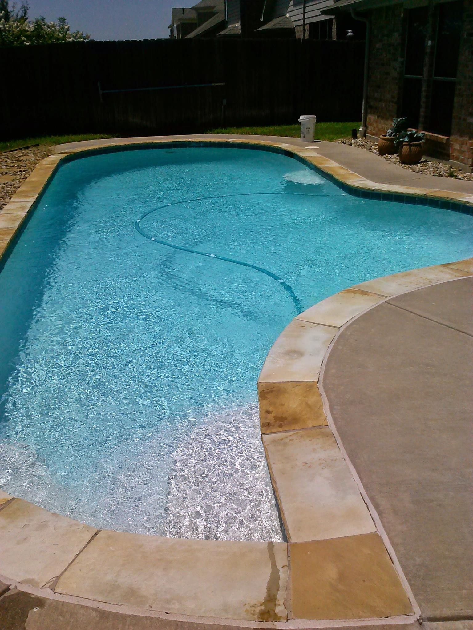 Swimming pool with light blue water and stone edging.
