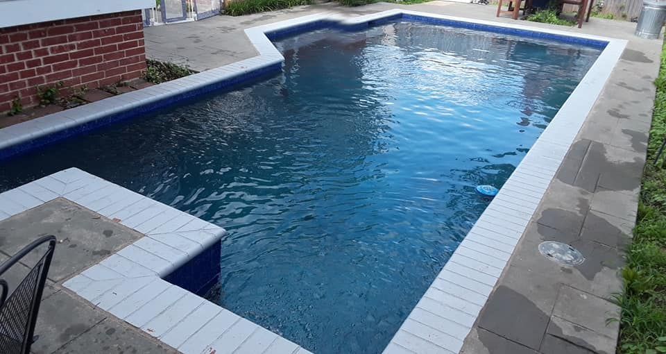 Pool with blue water and white tiled edges surrounded by concrete.