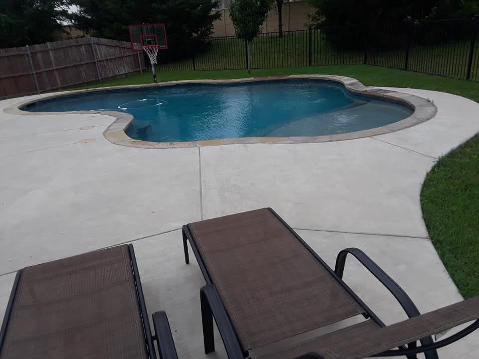 Pool with concrete deck, two lounge chairs, and a basketball hoop in the background.