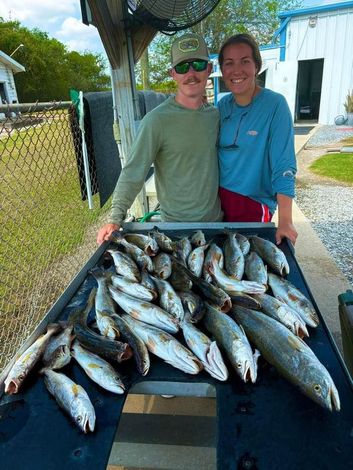 A man and a woman are standing next to a table full of fish.