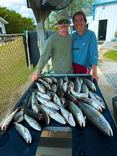 A man and a woman are standing next to a table full of fish.