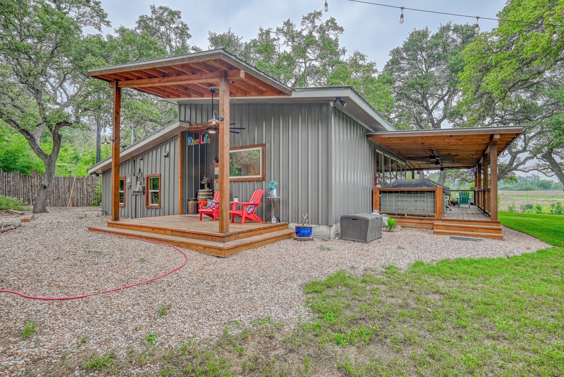 A small house with a porch and red chairs in a field.