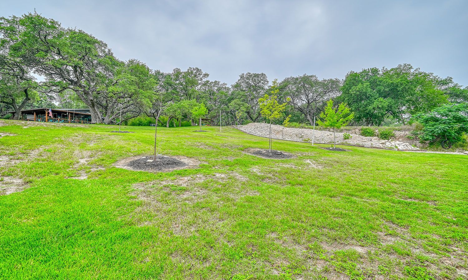 A large lush green field with trees and a house in the background.