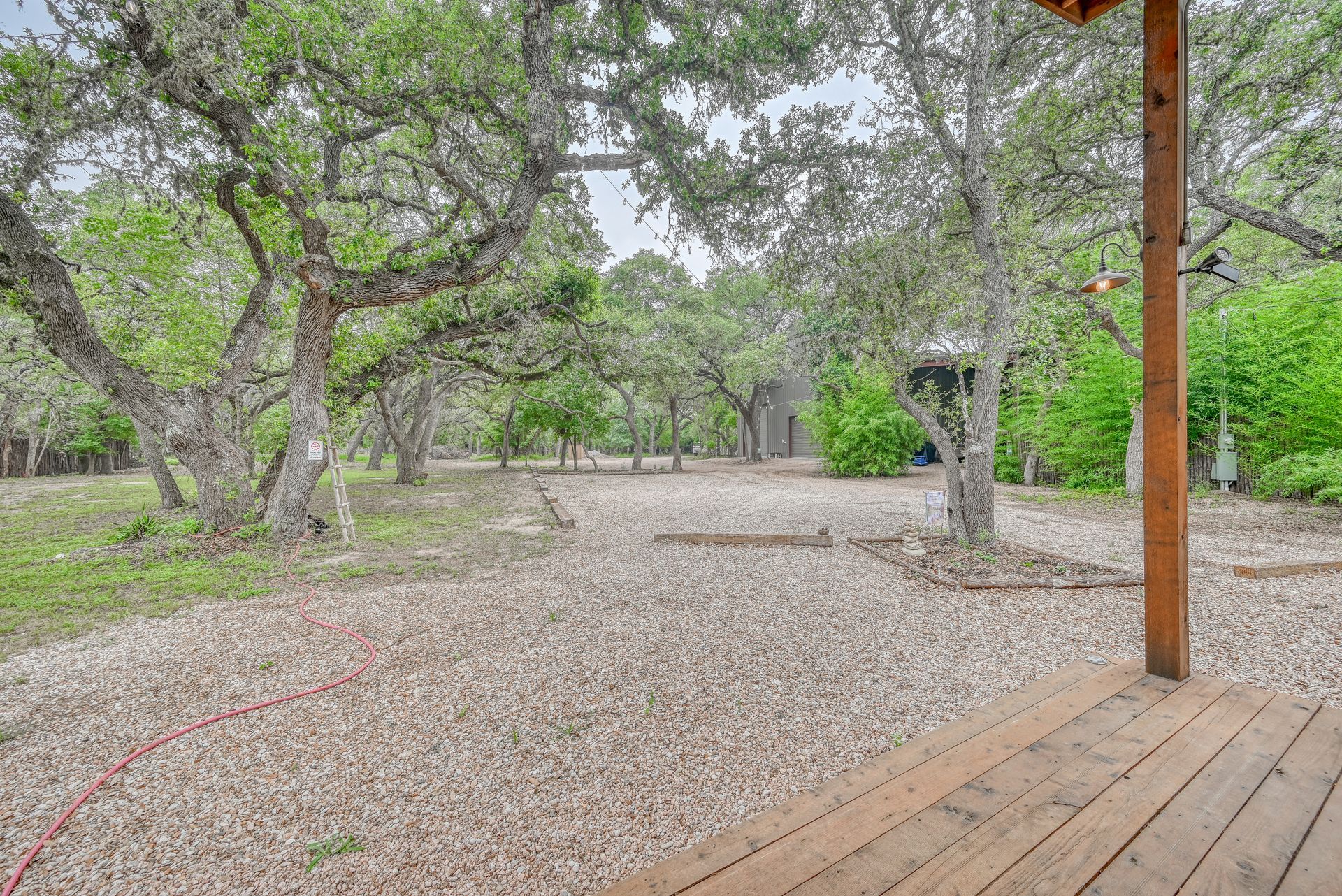 A wooden deck with trees in the background and a gravel driveway.