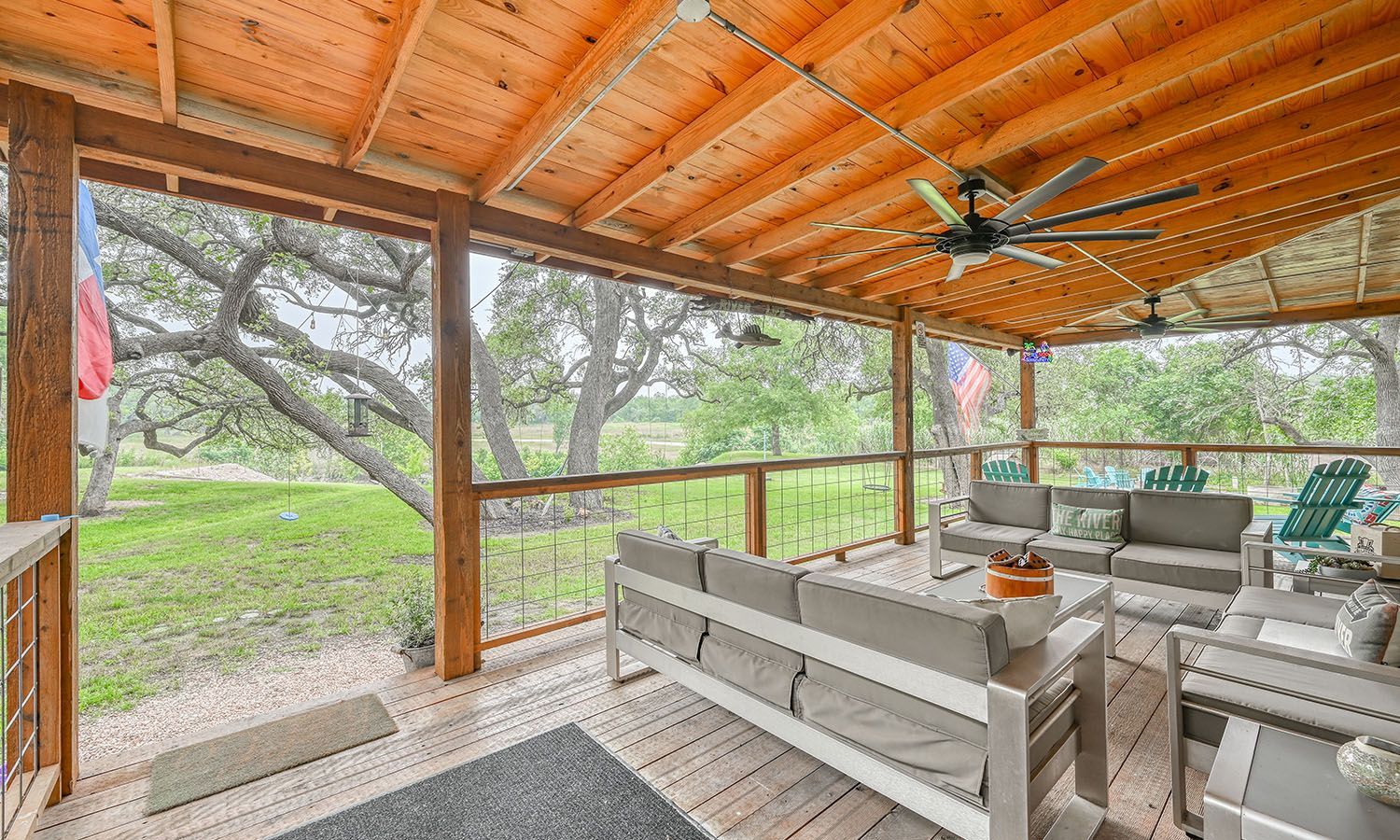 A screened in porch with a couch , chairs , and a ceiling fan.