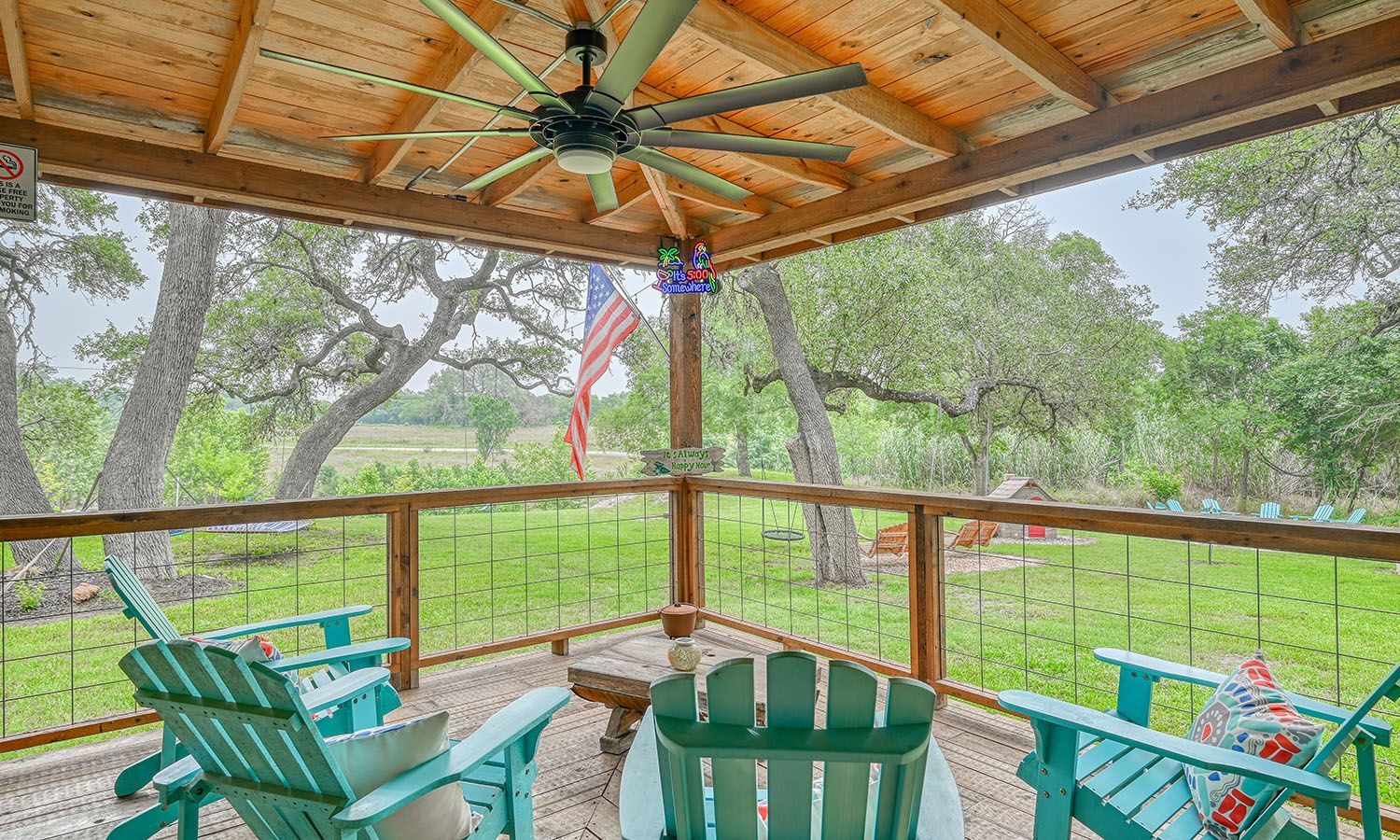 A screened in porch with blue chairs and a ceiling fan.