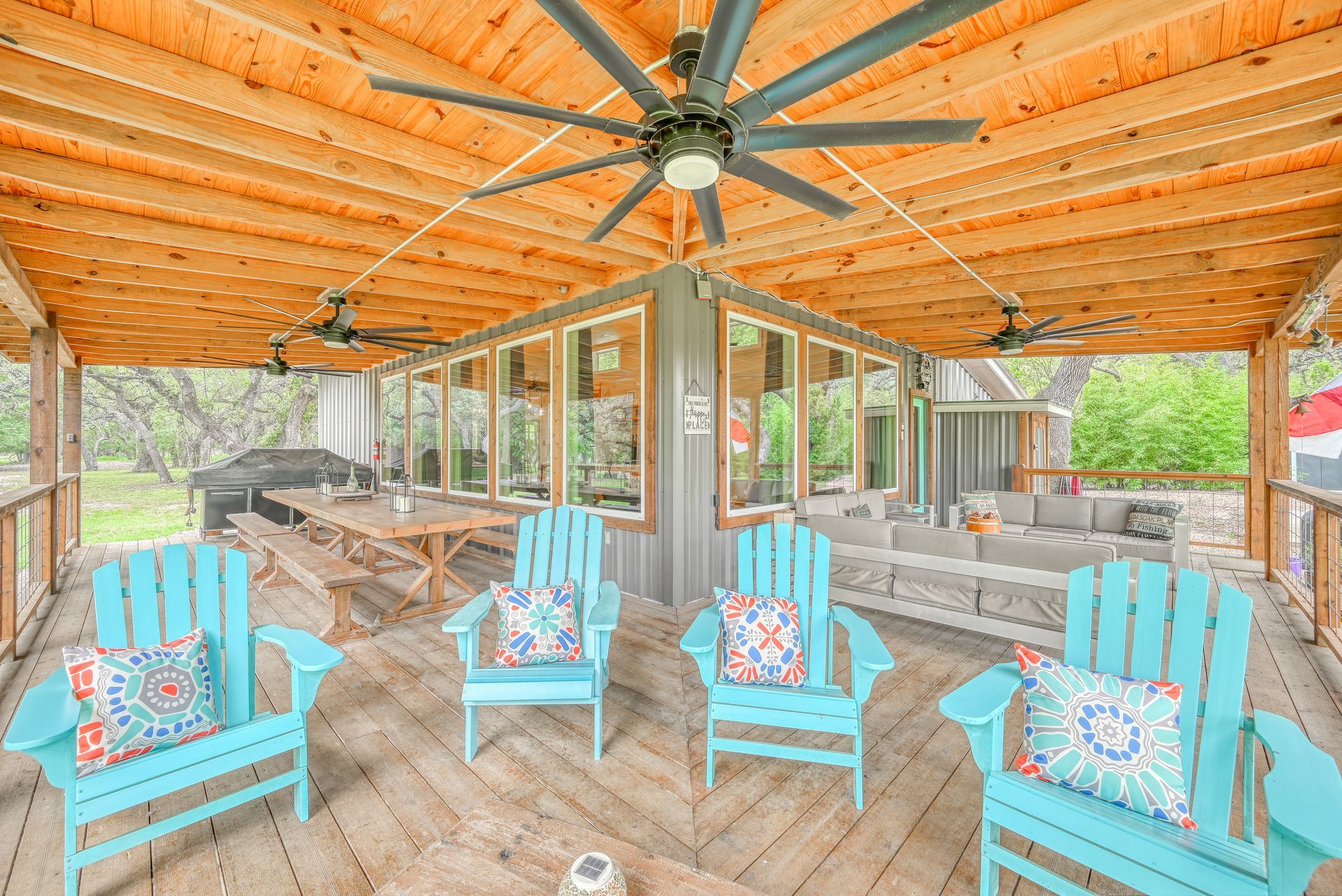 A screened in porch with blue chairs and a ceiling fan.