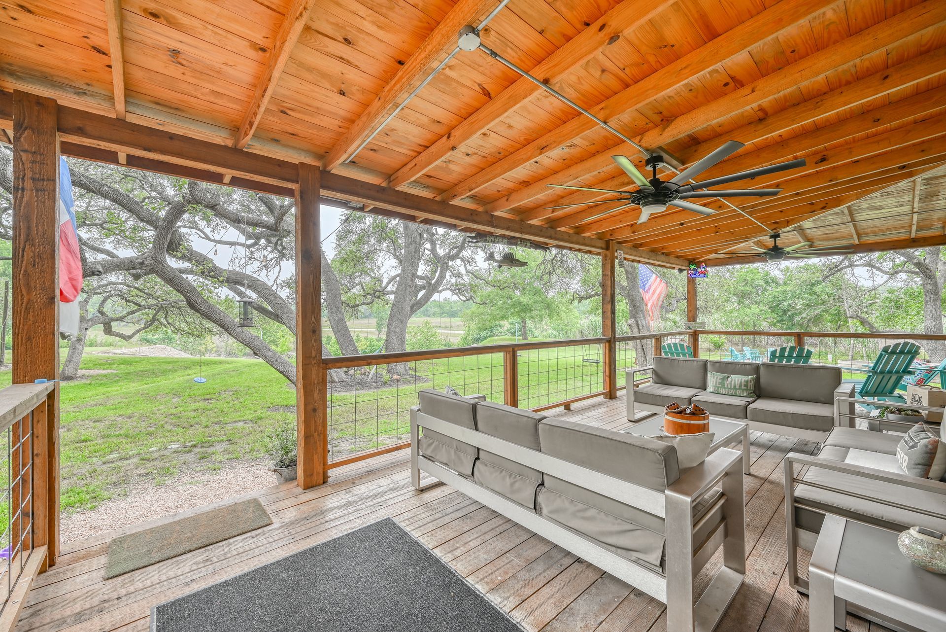 A screened in porch with a couch , chairs , tables and a ceiling fan.