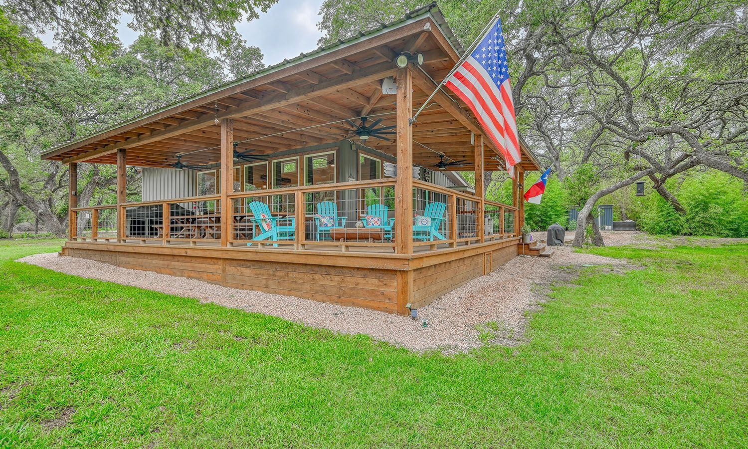 A wooden gazebo with a large american flag hanging from the roof.