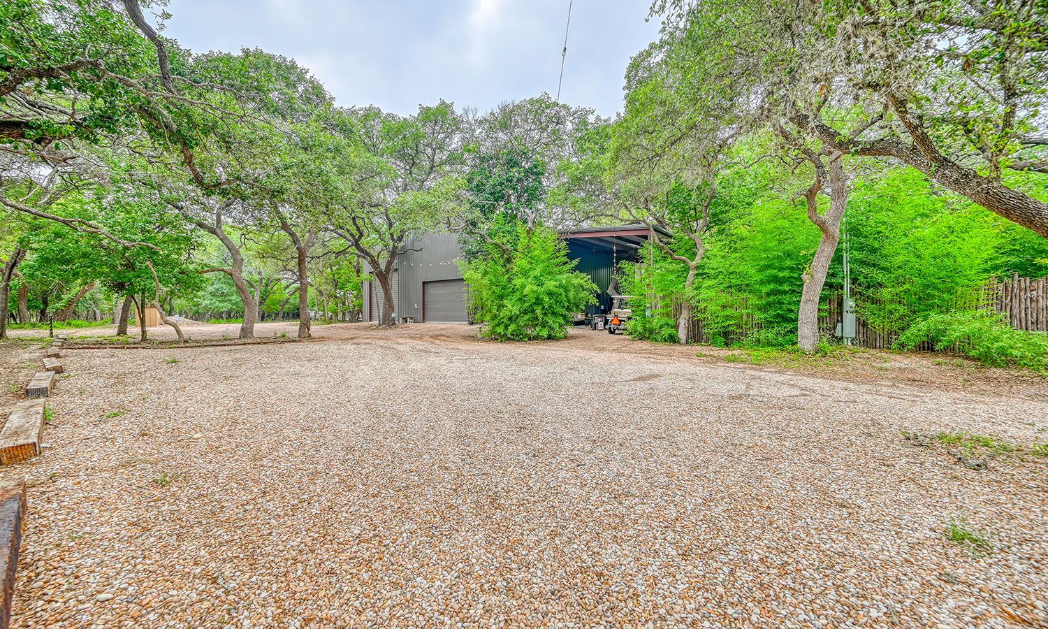 A gravel driveway leading to a house surrounded by trees.