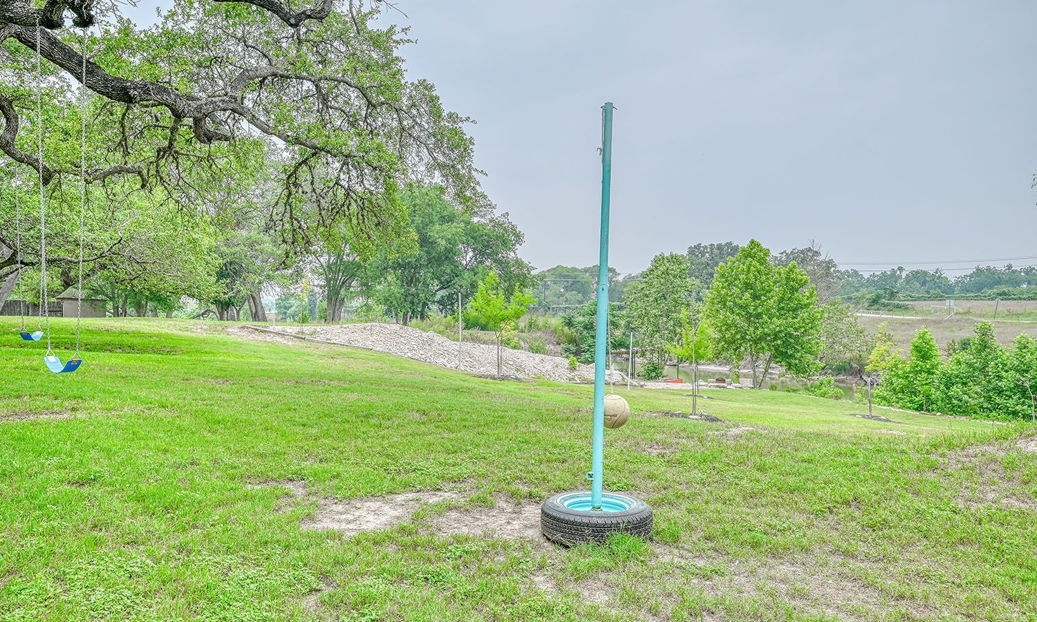 A volleyball net is sitting on top of a tire in a grassy field.
